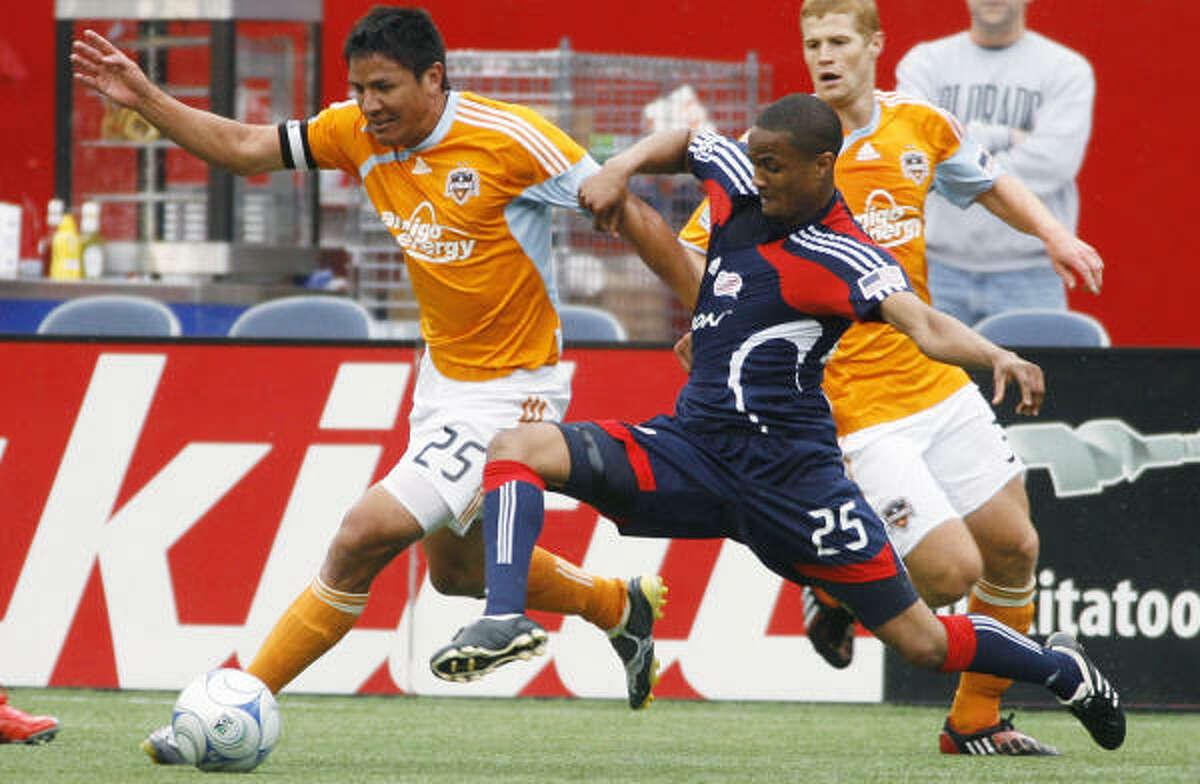 Dynamo forward Brian Ching, left, battles for the ball with Revolution defender Darrius Barnes during the second half.