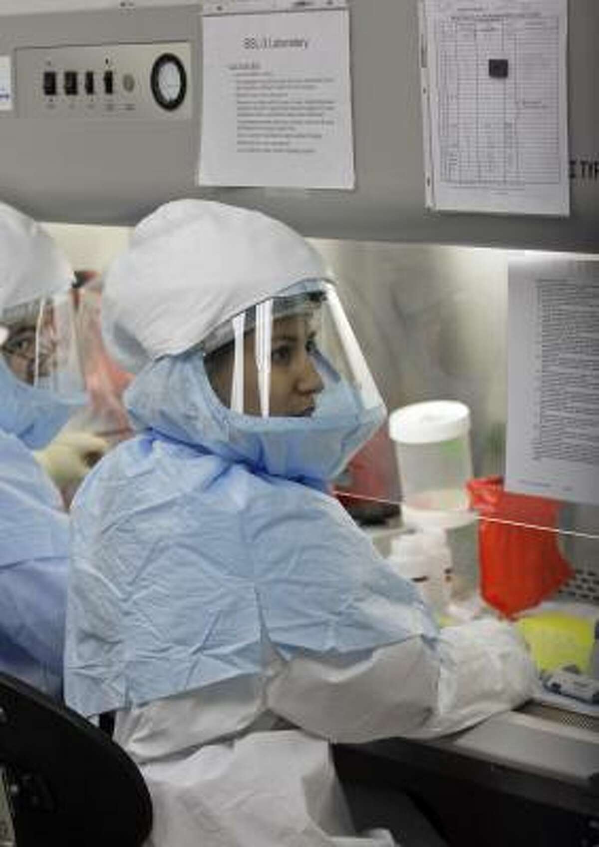 Lead scientist Lupe Garbalena, right, and microbiologist Gilbert Ortiz handle samples while testing for swine flu at the Houston Department of Health and Human Services.