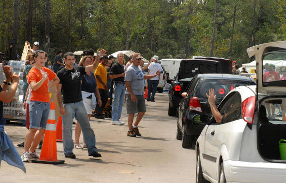 Kylie Phillips and Andrew Barton, of The Woodlands, smile and wave as cars pull into the POD. Photo: David Hopper, For The Chronicle