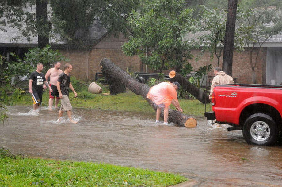 Neighbors banded together during Hurricane Ike to remove one of the two trees that fell across Tickner St. near Erickson St. in Conroe. The trees were blocking the street and one neighbor used a chainsaw to help remove it from the road. Photo: David Hopper, For The Chronicle