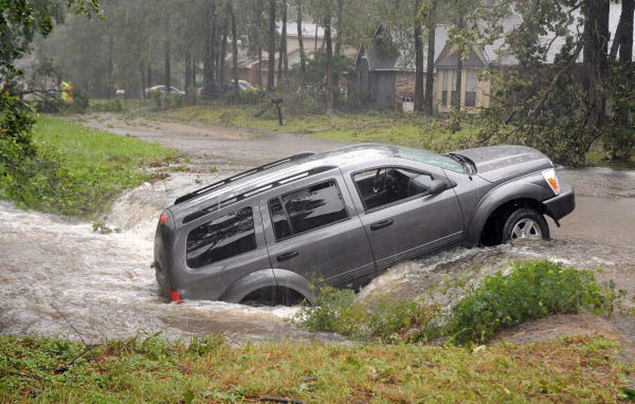 A driver and her infant were pulled from their SUV by residents on Hancock St, near Tickner St., in Conroe after she accidently backed her car into a creek while trying to turn around to avoid a fallen tree in the street. Photo: David Hopper, For The Chronicle