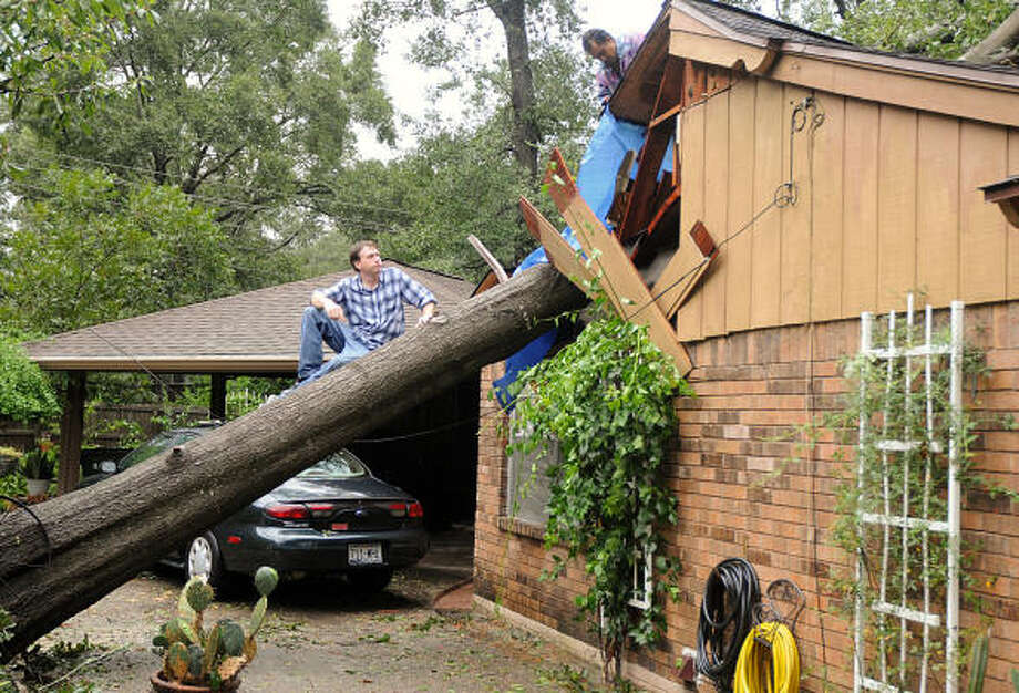 Sam Wilkinson sits in a tree that crashed into his mother's house, on Lilly Street near Thompson street, in Conroe. Wilkinson's mother was cooking when she heard a noise and saw the tree falling. She ran, and the tree crashed through the roof and landed on the stove where she had been cooking. Photo: David Hopper, For The Chronicle