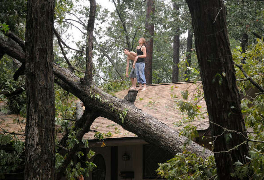 Residents try to get a bird's eye view of the damage to their house caused by a tree falling on the roof of their N. Thompson, near Lilly Blvd, home in Conroe. Photo: David Hopper, For The Chronicle