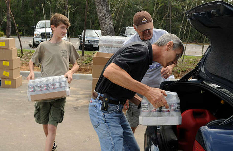 Tom Reed, of The Woodlands, places ice in the trunk as his son Ryan brings water to the car. Reed and four of his children volunteered at the Fellowship of The Woodlands Church POD. Photo: David Hopper, For The Chronicle