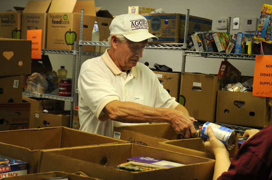 Volunteer Don Earnest, of Montgomery Methodist Church, places canned goods in a box at the Montgomery County Food Bank. Photo: David Hopper, For The Chronicle