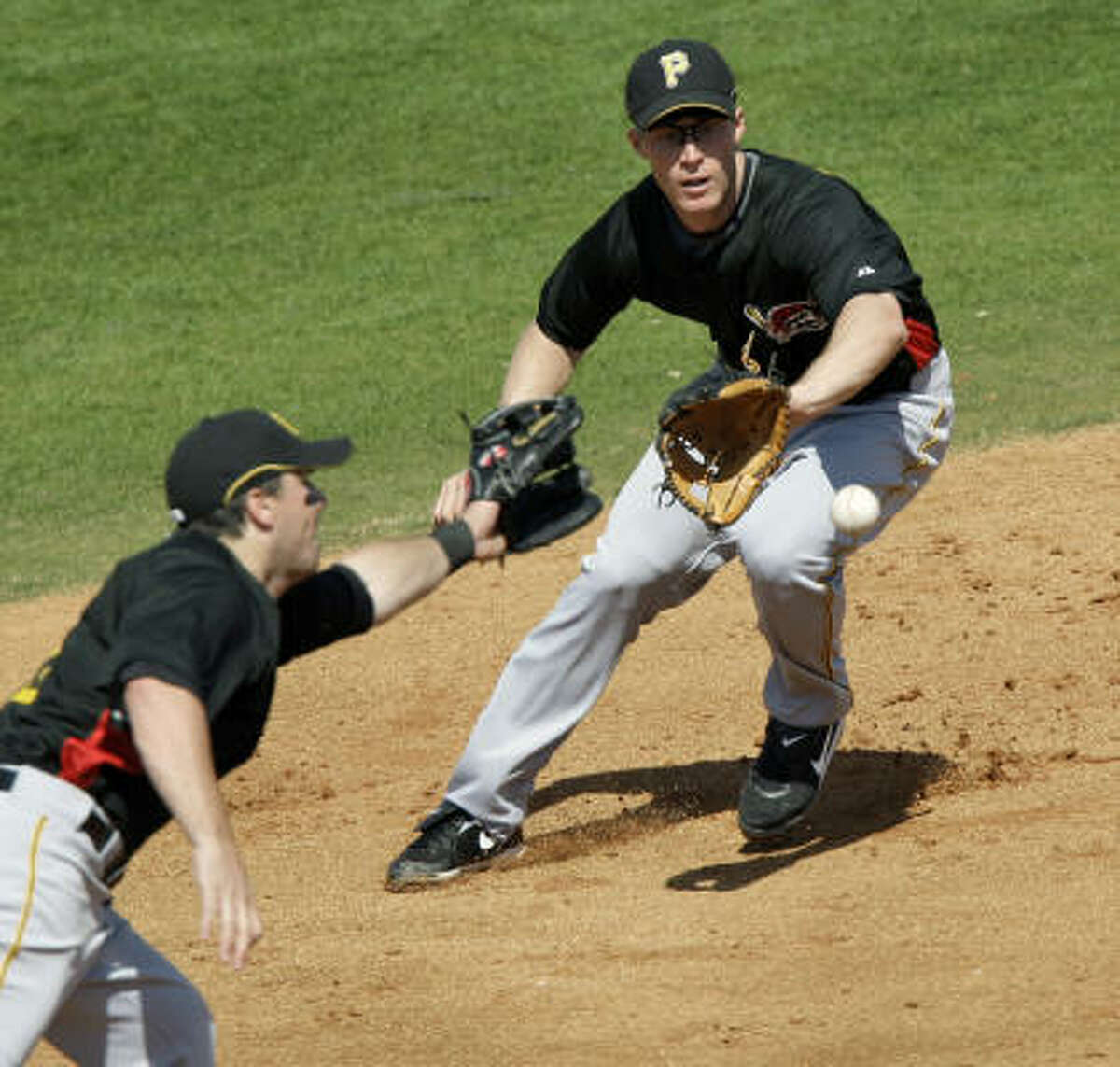 Pittsburgh Pirates shortstop Brian Bixler, right, fields a ball hit by Houston Astros' Darin Erstad as Pirates third baseman Andy LaRoche, left, reaches for the ball.