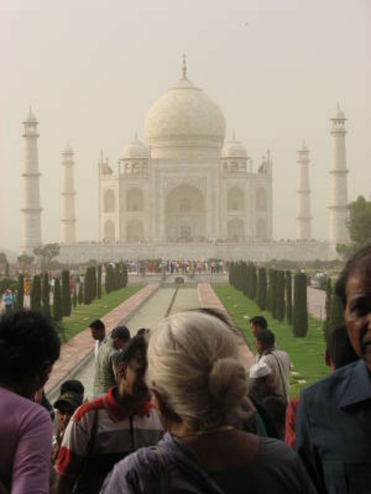 Even in a dust storm, the gardens of the Taj Mahal are packed with people.
