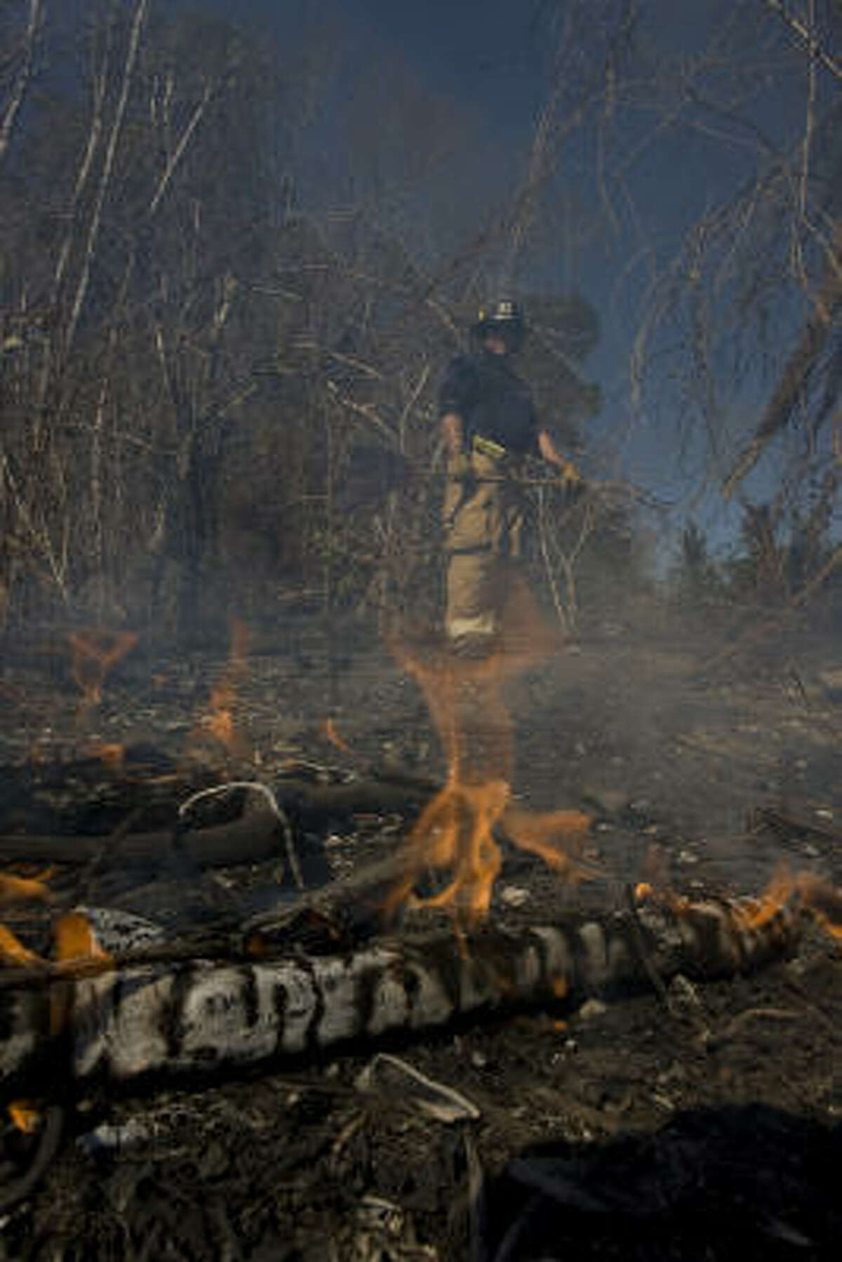 Houston firefighter Trey Bourgeois works on putting out a grass fire across from T.C. Jester Park in Houston. Firefighters were battling flames from a fire that started the night before.