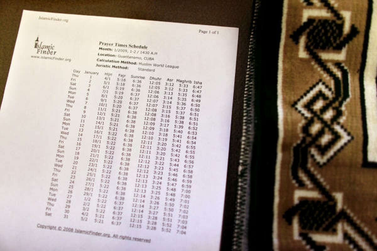 A downloaded and printed Muslim prayer schedule sits next to a prayer rug, inside a cell at Guantanamo's Camp 5 detention center at the U.S. Naval Base Wednesday, Jan. 21, in Cuba.