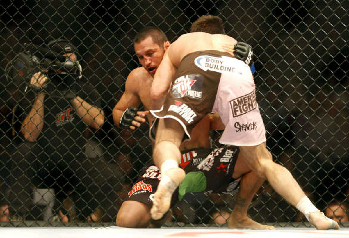 Rich Franklin pins Dan Henderson against the cage and tries to knee him.