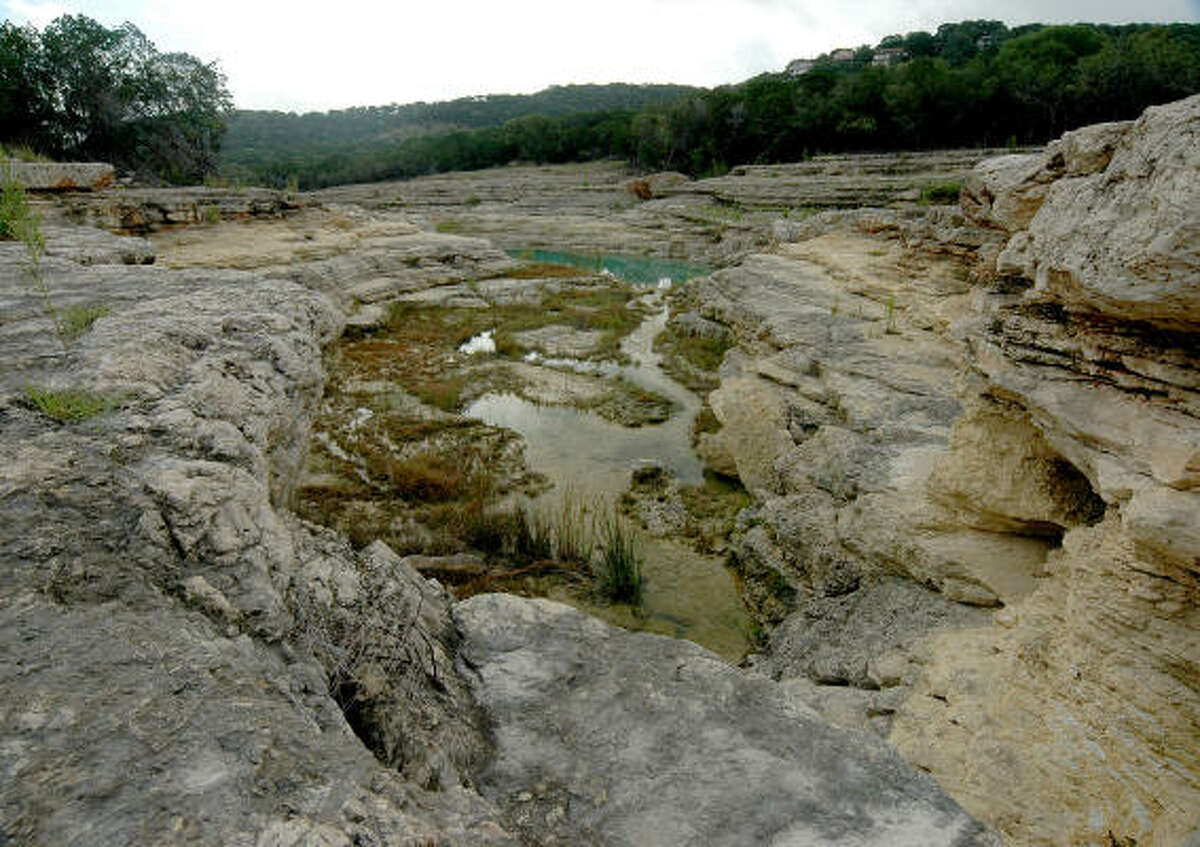 Below "Pride Rock," the photo shows the upper springs which provide water to the gorge. The springs issue from small faults and fractures, along which groundwater is flowing. The blue-green pool is home to a few fish that washed in with the flood.
