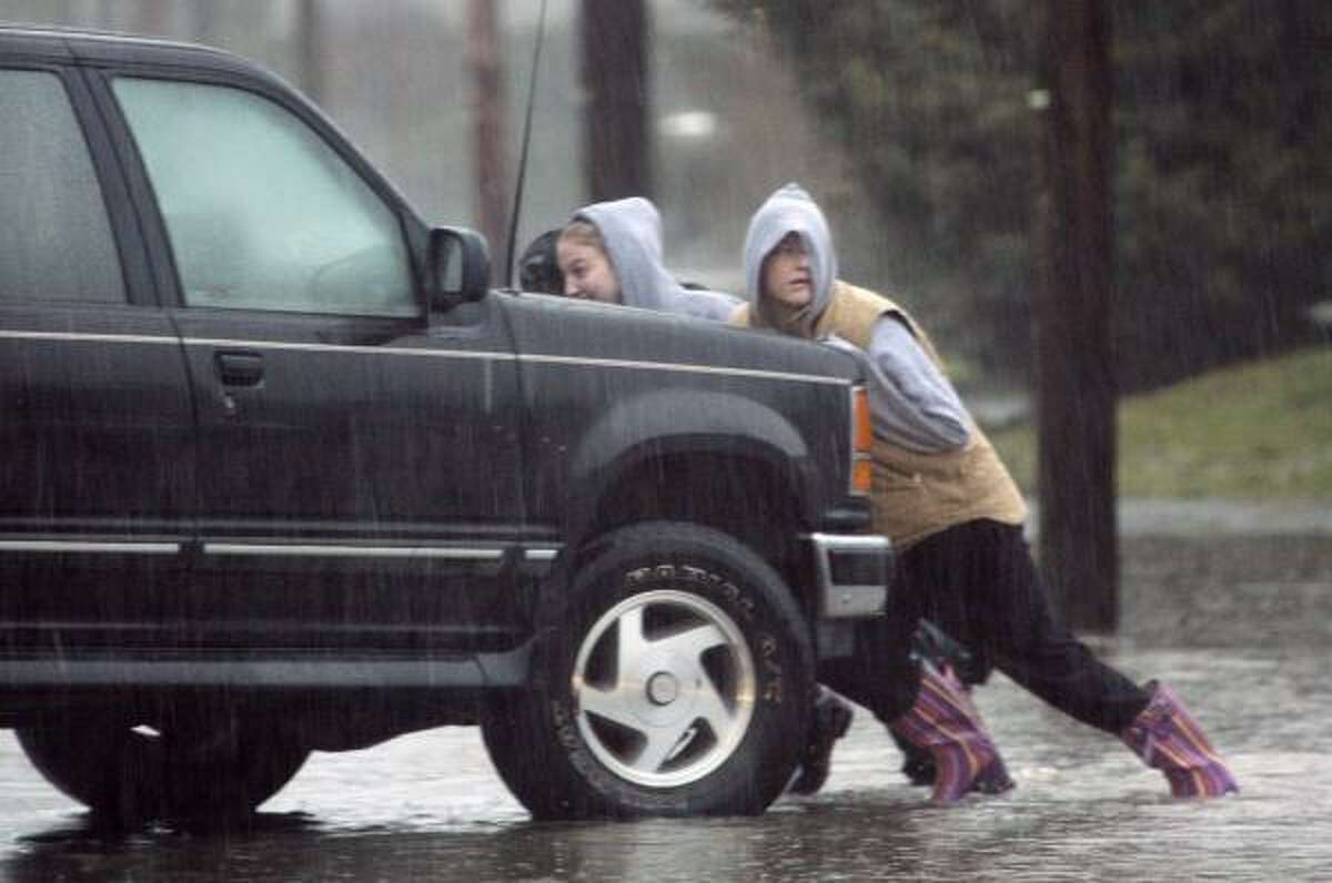 A group pushes a car out of a street on Jan. 8 where it stalled a day earlier in flood waters in Snoqualmie, Wash.