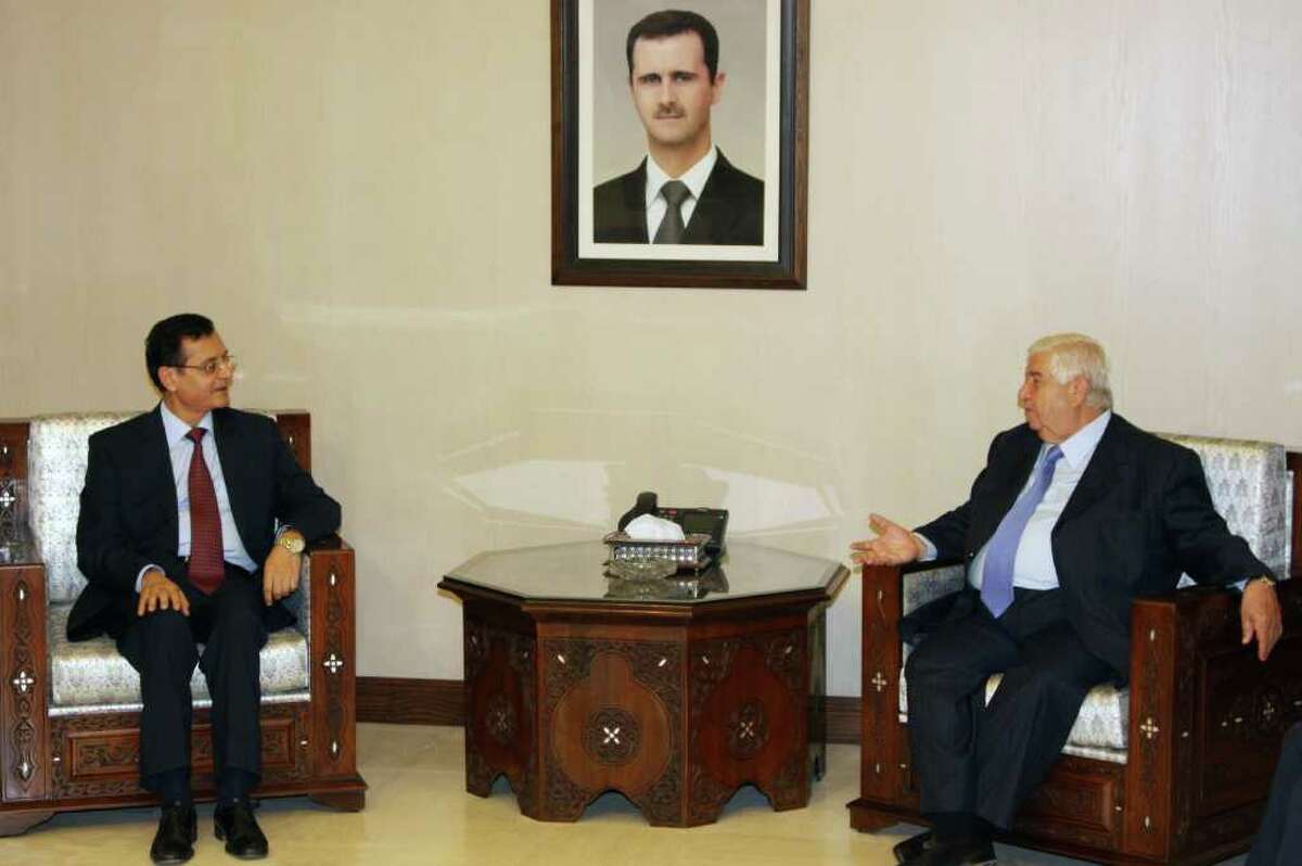 Syrian Foreign Minister Walid al-Moallem, right, meets with his Lebanese counterpart Adnan Mansour in Damascus, Syria, Sunday, Aug. 7, 2011. Mansour met earlier in the day with Syrian President Bashar Assad, who has stressed that his country is moving on steadily with the process of reforms and would simultaneously deal with outlaws to preserve the country's security. Portrait of Syrian President Bashar Assad at centre. (AP Photo/Bassem Tellawi)