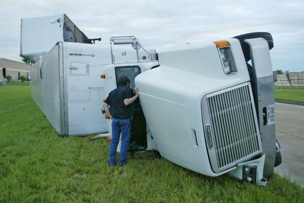 Tim Ellsworth of Richland Hills, Texas, peers into the cab of his overturned semi tractor trailer today. High winds and heavy rain were part of the powerful storms in Arkansas, Texas, and Oklahoma, causing flooding and power outages for thousands of customers.