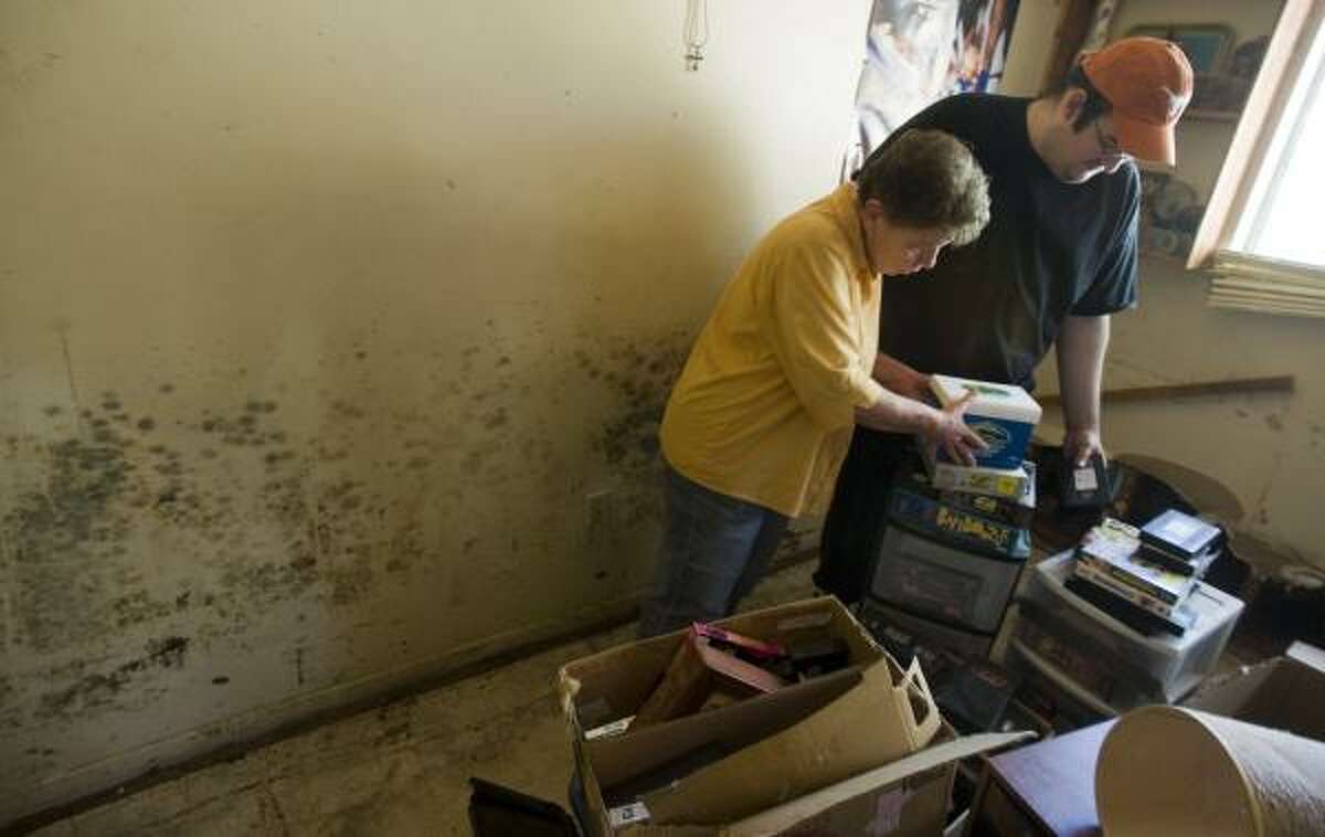 Barbara Kiker, 66, and her son Houston Kiker, 27, sort through belongings in their mold-infested Seabrook home last week.