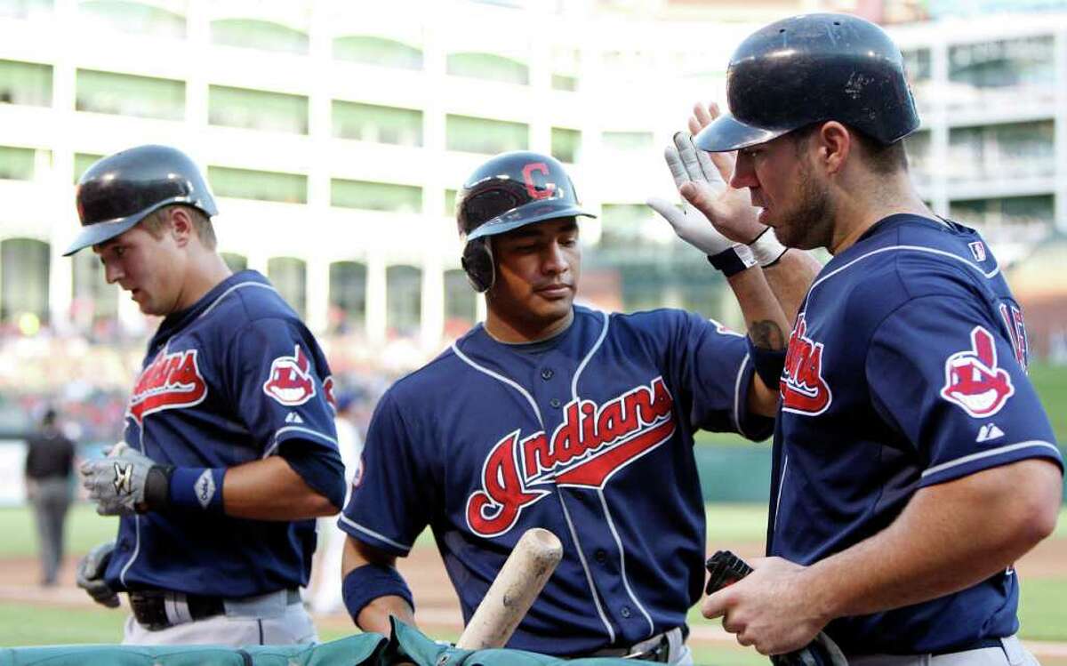 Cleveland Indians' Ezequiel Carrera, center, congratulates Travis Hafner, right, after Hafner scored on a sacrifice fly by Lonnie Chisenhall, left, in the second inning during a baseball game against the Texas Rangers Sunday, Aug. 7, 2011, in Arlington.