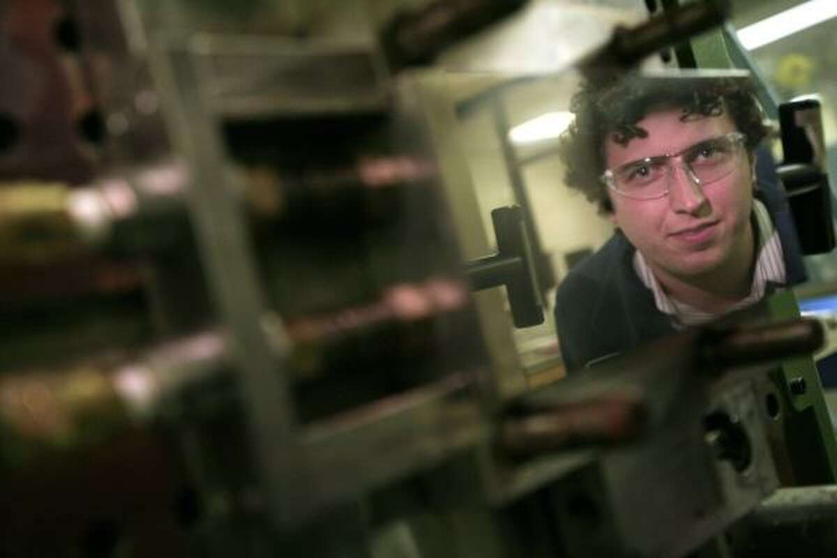 Jacob Jones, a chemical technologist at Dow, is reflected in an injection mold that produces samples of elastomer.