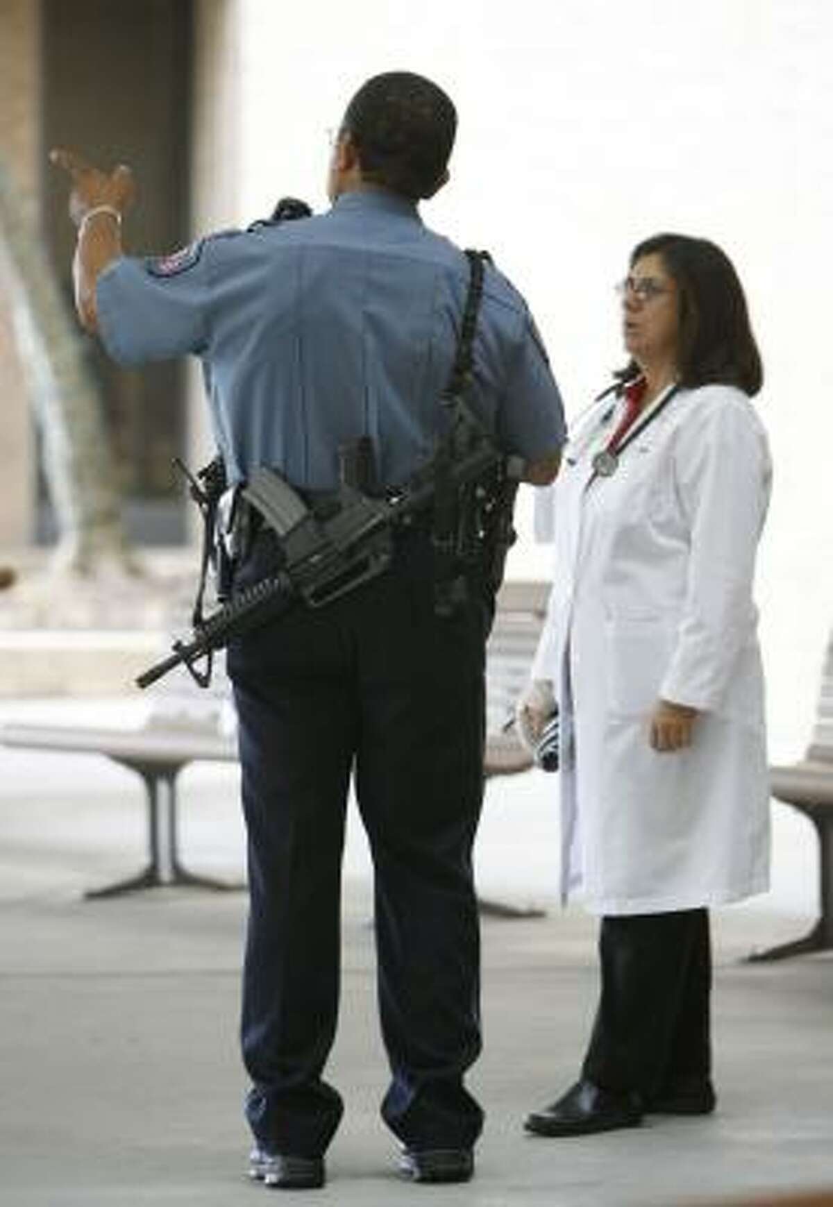 A UTMB officer guards Galveston's John Sealy Hospital with semiautomatic weapons as the hospital reopens Monday.