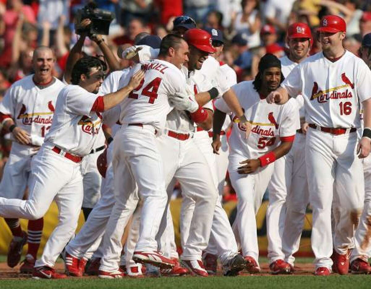 St. Louis' Rick Ankiel (24) is besieged by teammates after his two-run, two-out single in the ninth lifts the Cardinals past the Cubs on Saturday.