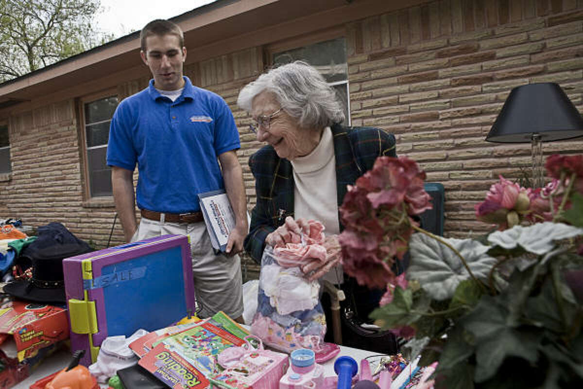 A garage sale customer checks out merchandise with the help of Ben Weissenstein, 17, who founded and runs Grand Slam Garage Sales.