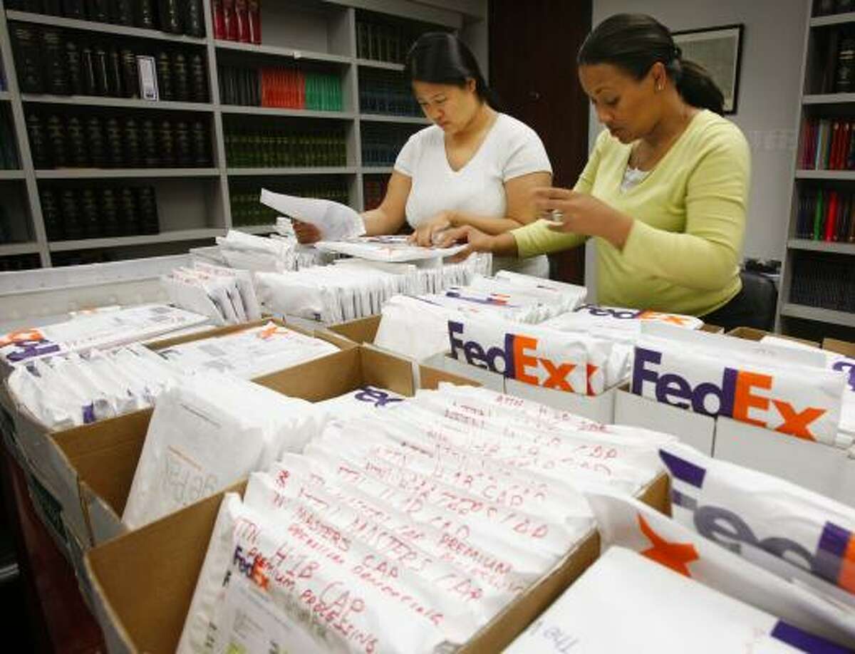 Jacklyn Hoang, left, and Tiffany Broussard double-check H1-B visa applications at the Houston law firm of Quan, Burdette and Perez. The firm shipped out about 500 applications for its clients.