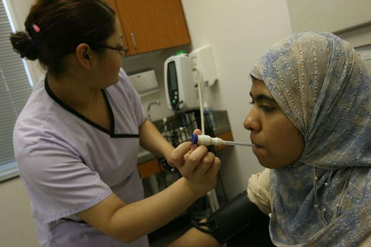 Adriana Silvas takes Madiha Merchant's temperature at an Ibn Sina Foundation community clinic.