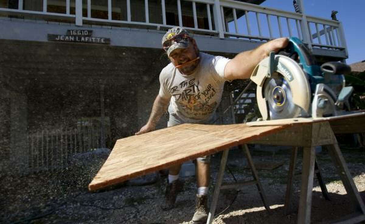 Robert Sawyer cuts plywood Wednesday to board up a home on Jamaica Beach.