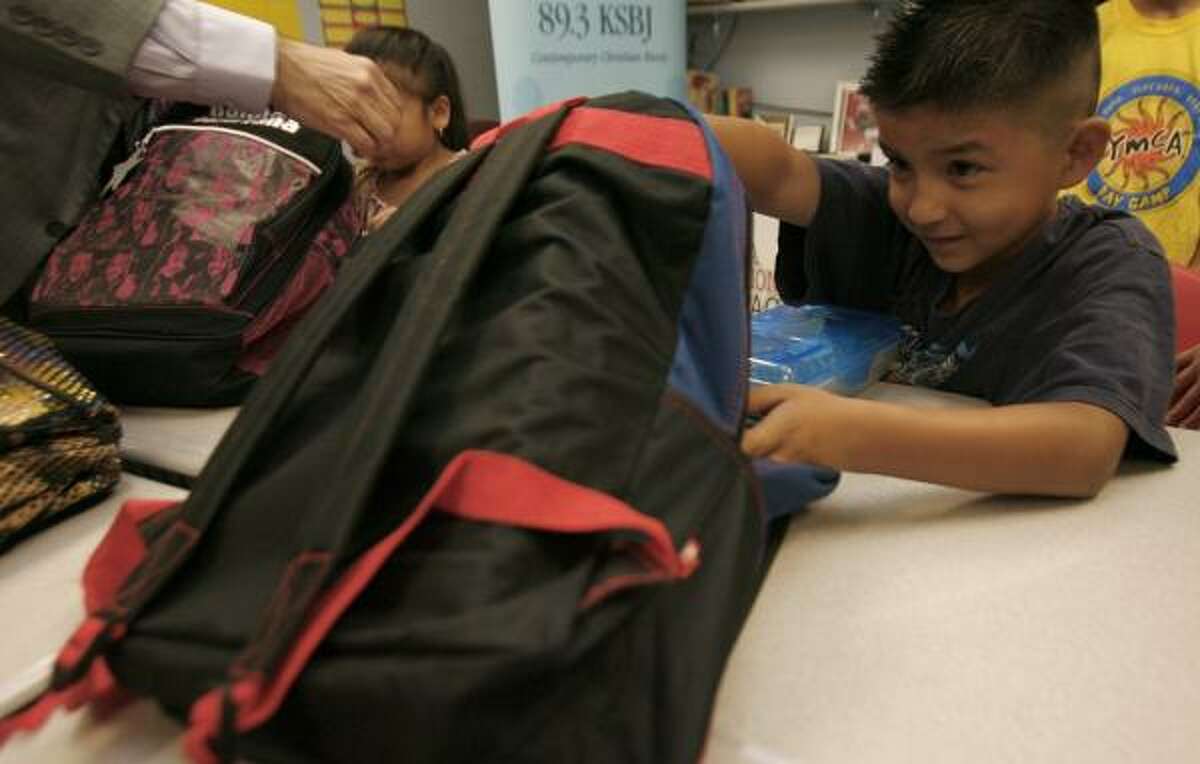 Jonathan Torres, 7, peeks into a backpack he received Monday that's full of school supplies. Through YMCA Operation Backpack, the YMCA of Greater Houston hopes to fill the needs of more than 50,000 children preparing for the new school year.