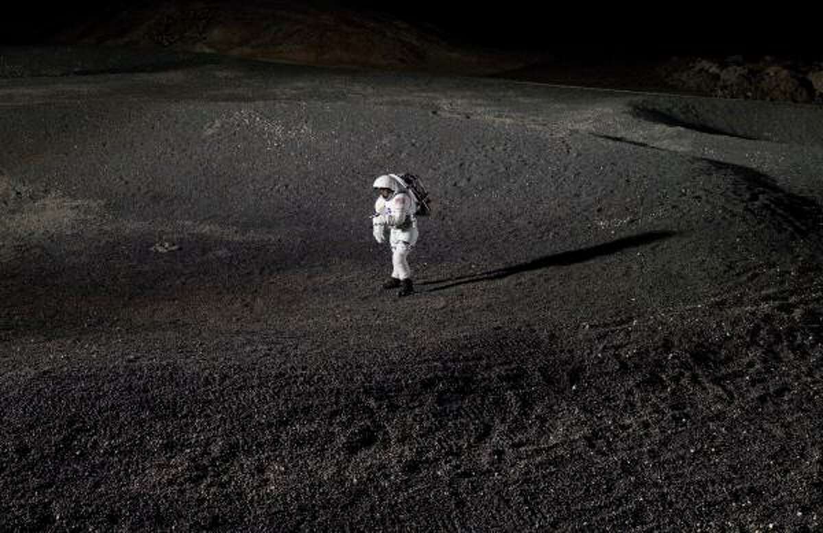 A prototype spacesuit is tested in an artificial crater in the Lunar Yard, a test facility at Johnson Space Center that replicates the moon's surface.