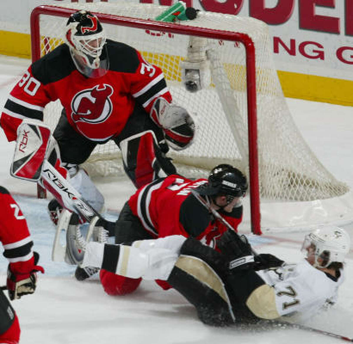 The Penguins' Evgeni Malkin is taken down by the Devils' Paul Martin in front of the net.