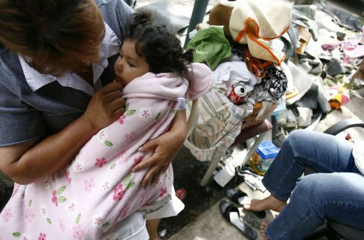 Maria Suarez comforts her sick niece, Rosalinda Galvan, 1, at the Casa Real Apartments at Little York near I-45.