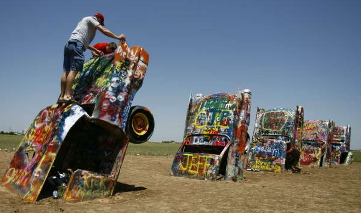 A father and son from Arkansas write their names on one of the Cadillacs at Cadillac Ranch, west of Amarillo.