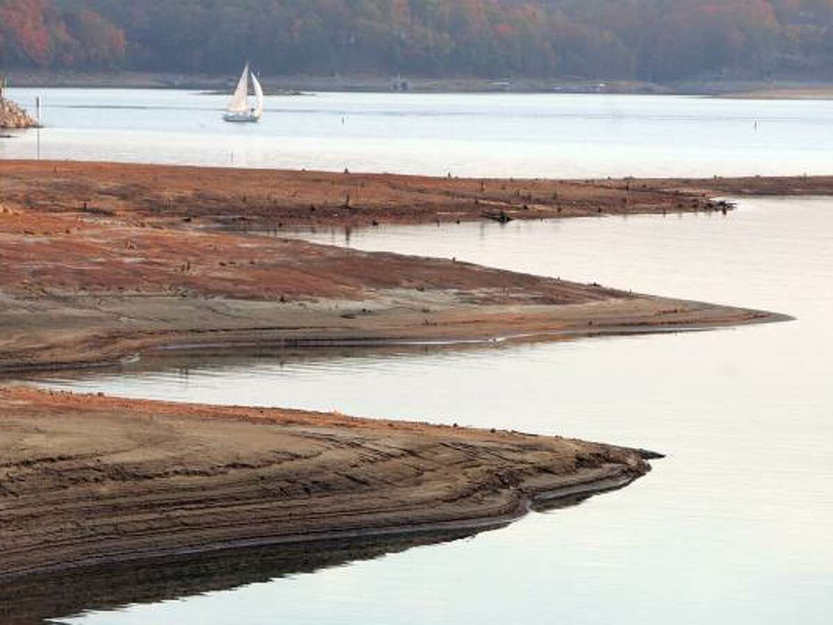 A sailboat glides past the exposed bottom of Lake Lanier in Flowery Branch, Ga. Gov. Sonny Perdue has ordered water restrictions in the Peach State, launched a legal battle and asked for federal help.
