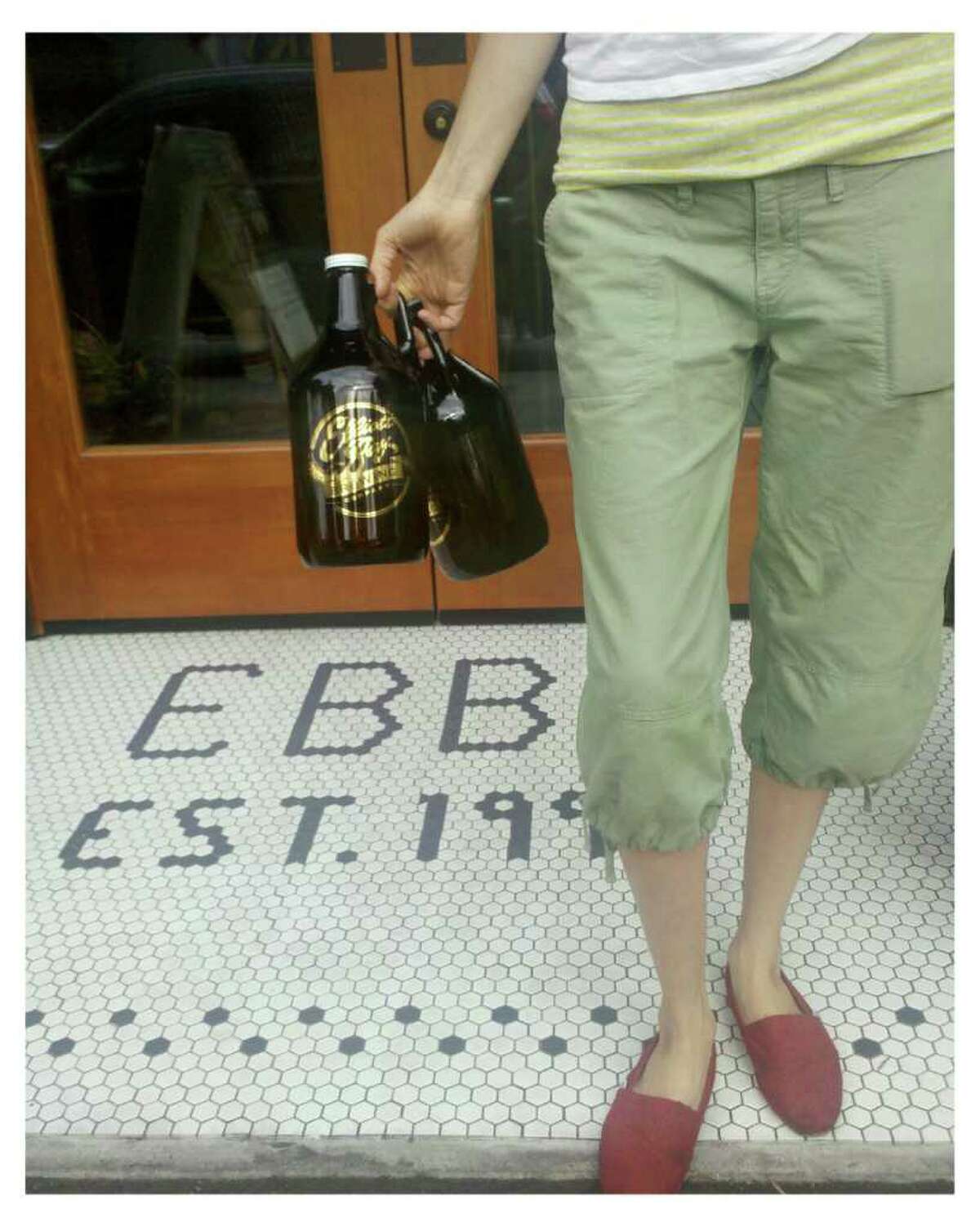 A woman holds beer growlers near the entrance of Elliott Bay Brewery in West Seattle on Tuesday, Aug. 9, 2011.