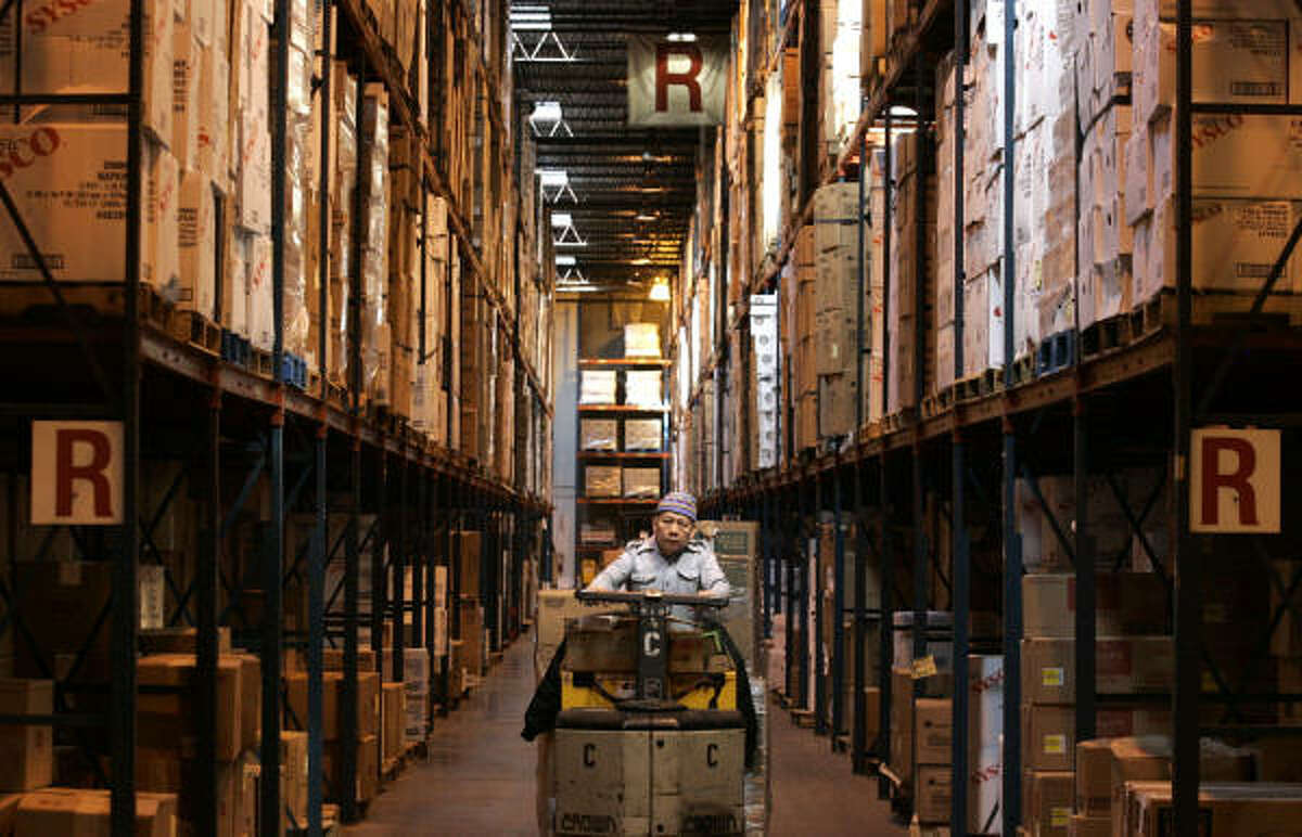 A Sysco warehouse worker drives down one of the packed aisles in his forklift in the distribution facility Wednesday.