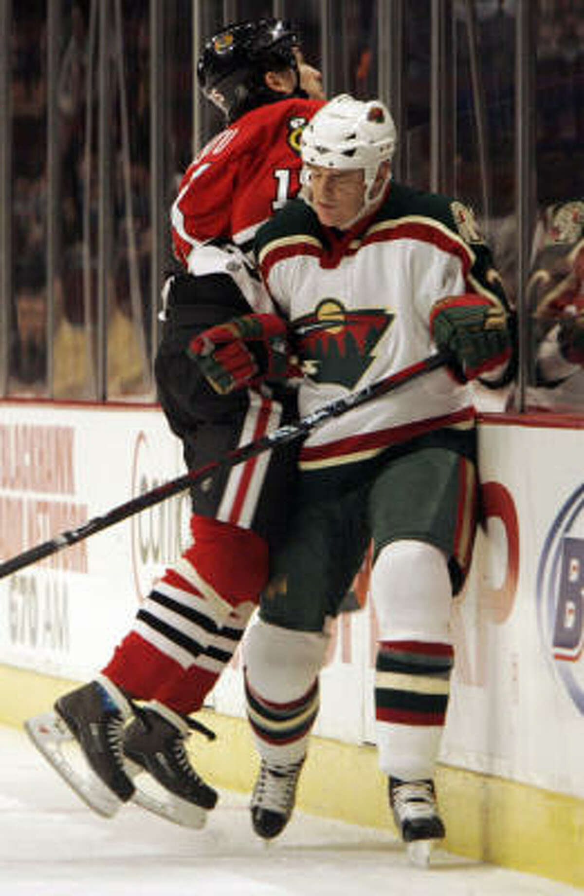 Former Aeros player Kurtis Foster, now with Minnesota, takes a check from Tuomo Ruutu of host Chicago.
