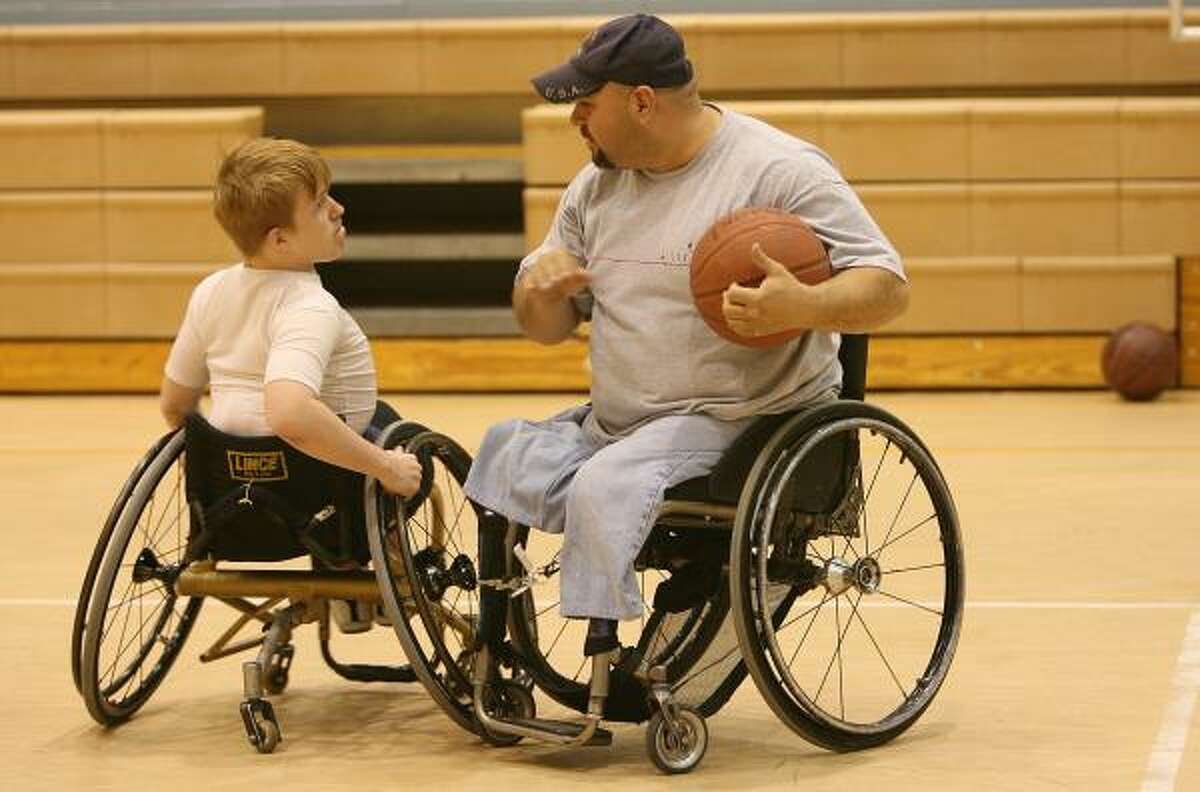 Oziel Flores, right, discusses a play with Trevor McCuiston during wheelchair basketball practice.