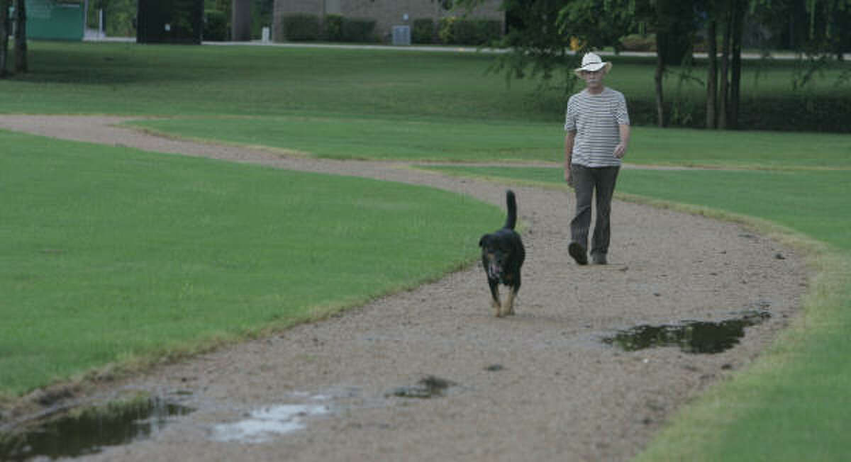 James Maverick walks his dog along a new trail in Missouri City's American Legion Park earlier this month. The trail was built with funds generated by Missouri City's park dedication ordinance, similar to the one being developed in Houston.