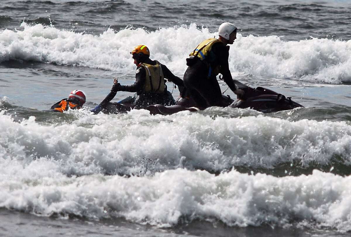 Surf rescue swimmers Eddie Mendez and Will Green pull Dale Ostrander aboard their jet ski after finding him in the surf off the Cranberry Road beach approach near Long Beach on Friday,. The team searched for the boy for nearly 15 minutes before finding him. (AP Photo/Damian Mulinix/Chinook Observer)