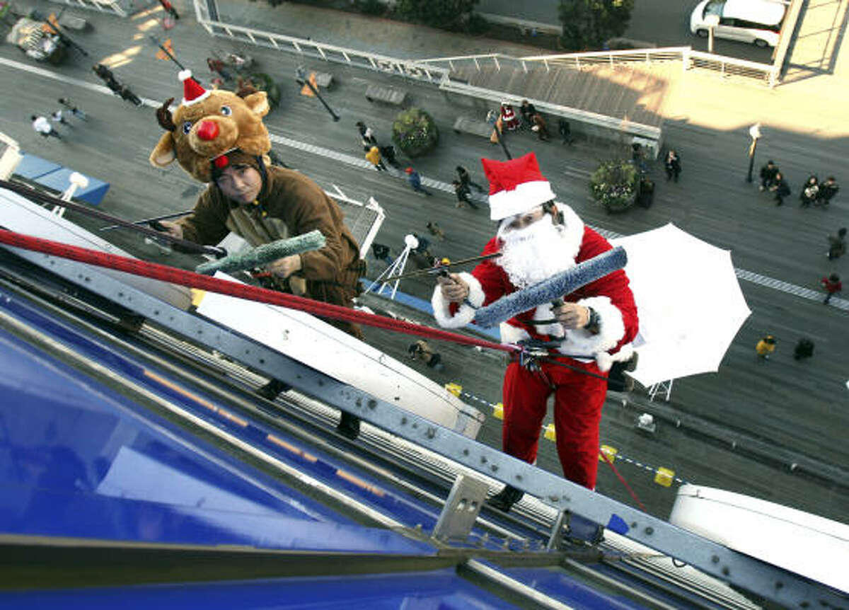 Workers in a Santa Claus and reindeer costume clean an office building's windows in Tokyo on Dec. 23.