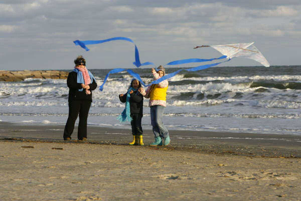 Jan.3 | Sarah Lathrop, 9, front, her sister Rachel Lathrop, 7, and mother Susan Lathrop, all of Montgomery, fly a kite on the beach. | Galveston, Texas