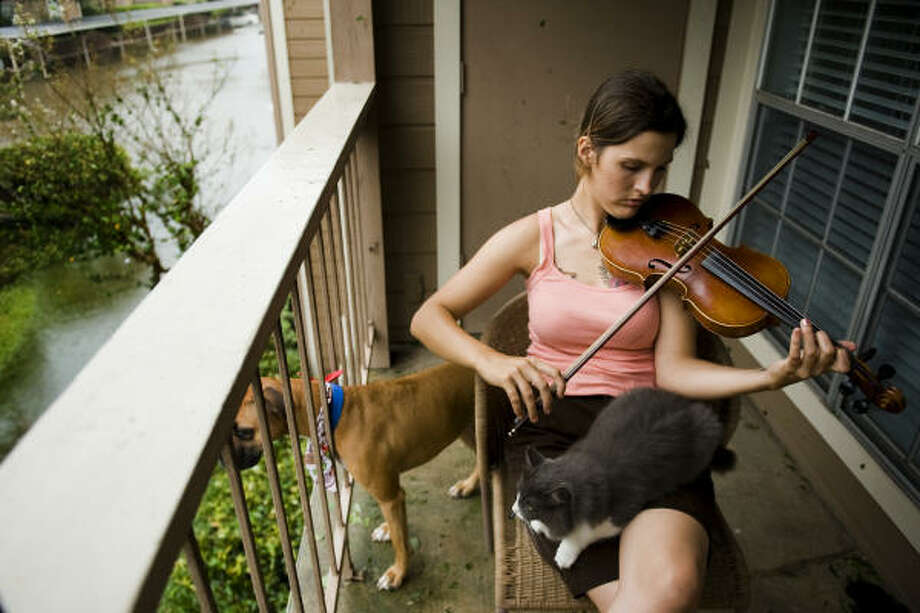 Soothing sounds | | Gina Williamson serenades her dog and cat on the balcony of her apartment complex on White Oak in the Heights. "There's nothing else to do but sit here," she said. Williamson, who works at a nearby animal hospital, planned to report to duty to care for the boarded animals of evacuees. | Sept. 13 | Houston Photo: Smiley N. Pool, Houston Chronicle