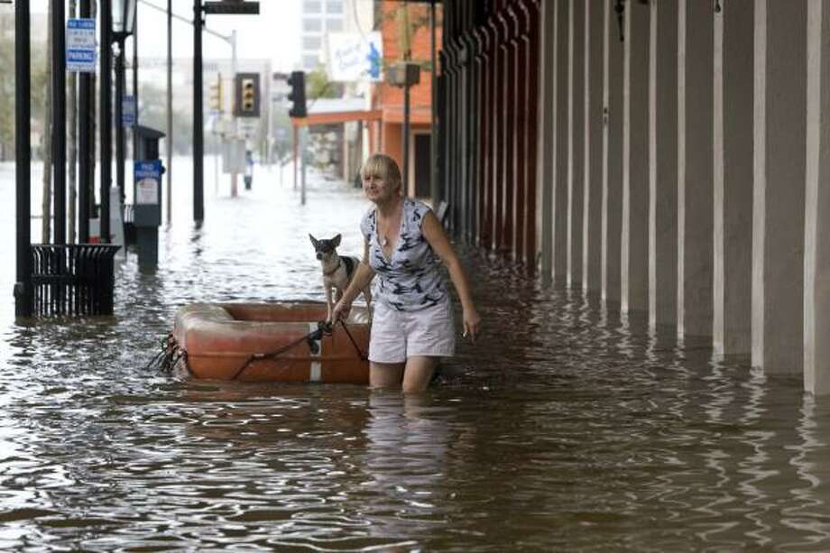 Getting around | Leslie Sundell floats her dog on a life raft as she walks along The Strand after the hurricane. | Sept. 13 | Galveston Photo: Brett Coomer, Houston Chronicle