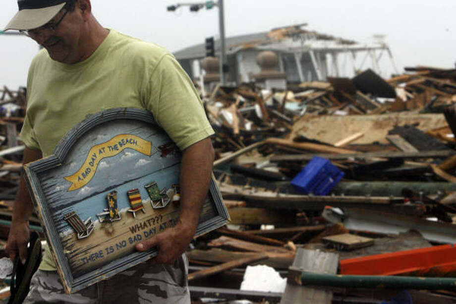 Sign of irony | Henry Vasquez salvages a sign from the remains of Murdoch's Pier and Hooters that reads, "A bad day at the beach. What??? There is no bad day at the beach." | Sept. 13 | Galveston Photo: Johnny Hanson, Houston Chronicle