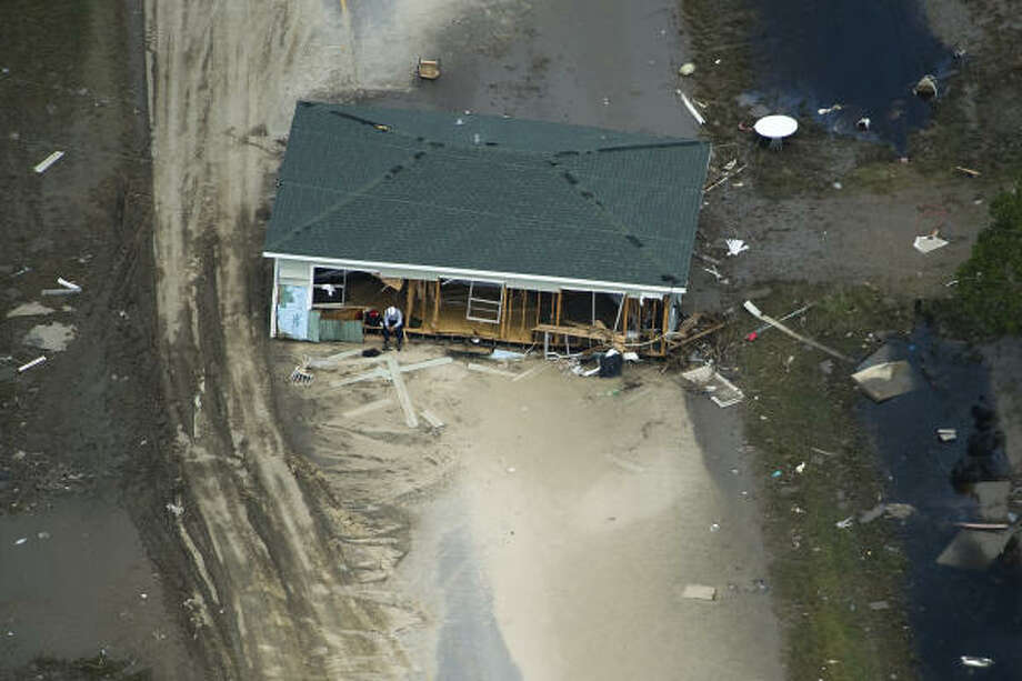 Weary | A search worker rests on the porch of a house pushed askew during the hurricane. | Sept. 15 | Crystal Beach Photo: Smiley N. Pool, Houston Chronicle