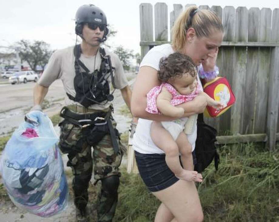 A way out | Ellie Cox carries her 6-month-old daughter, Jazya, as an unidentified California National Guardsman helps them to a helicopter so they can be evacuated to Texas City. | Sept. 13 | Galveston Photo: Melissa Phillip, Houston Chronicle