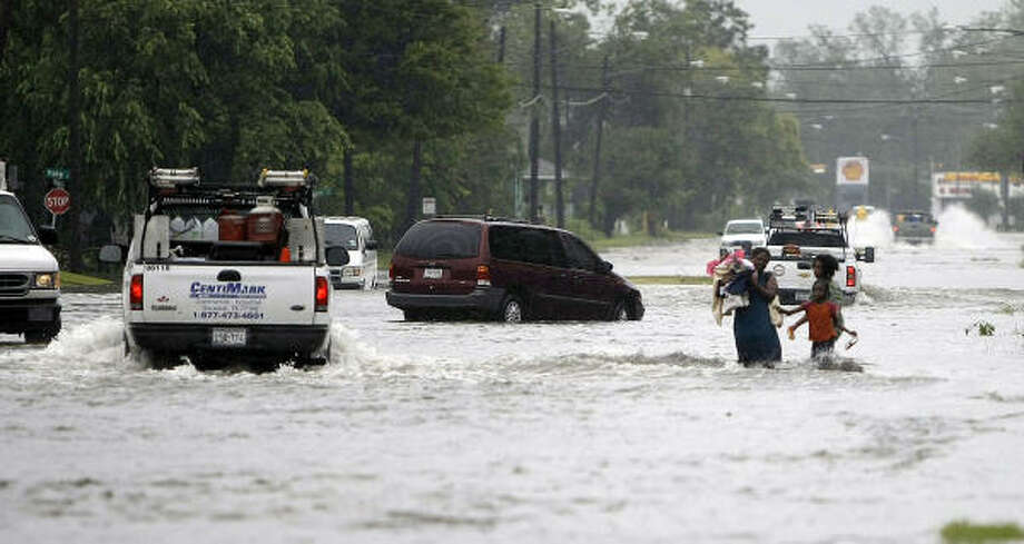 Perilous walk | A woman and her children wade through floodwaters on Yale in Independence Heights. | Sept. 14 | Houston Photo: Karen Warren, Houston Chronicle