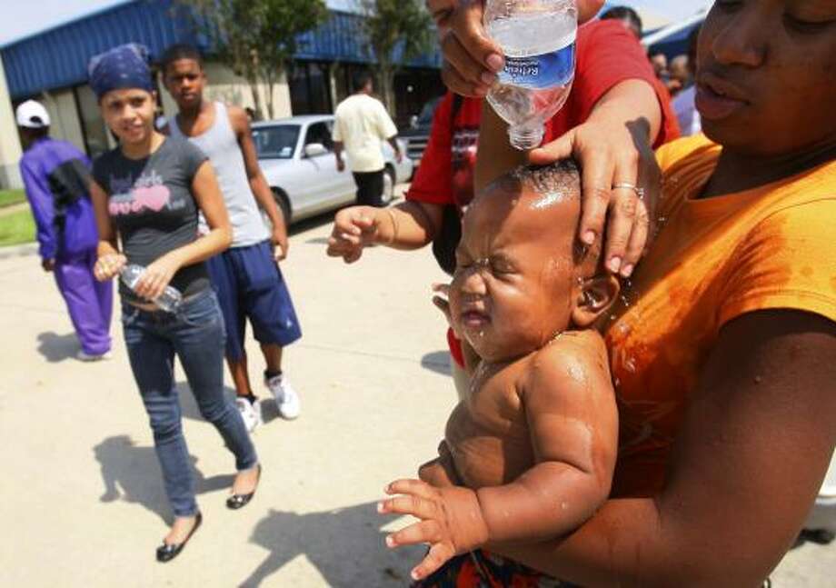 Bottle up | Tiffany Cunningham cools off baby Isiah, 10 months old, as they wait in line to get supplies at a FEMA distribution hub. They were in line for more than 4 hours. | Sept. 15 | Houston Photo: Mayra Beltran, Houston Chronicle