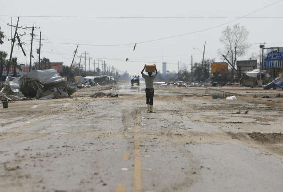 Food delivery | Michael Clow, who rode out the hurricane with his two cats, carries a box of MREs. He said he did not plan to leave the hard-hit area. | Sept. 17 | Port Bolivar Photo: Sharon Steinmann, Houston Chronicle