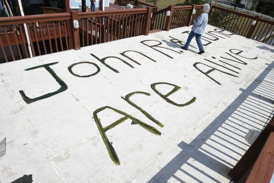 Sign of life | June Peveto, 59, walks over a sign she painted after the storm passed. "I was hoping someone would see it from the air and let our family and friends know we were OK," she said. Peveto and her husband, John, 75, were rescued by Army National Guard soldiers four days after the hurricane. | Sept. 17 | Crystal Beach Photo: Sharon Steinmann, Houston Chronicle